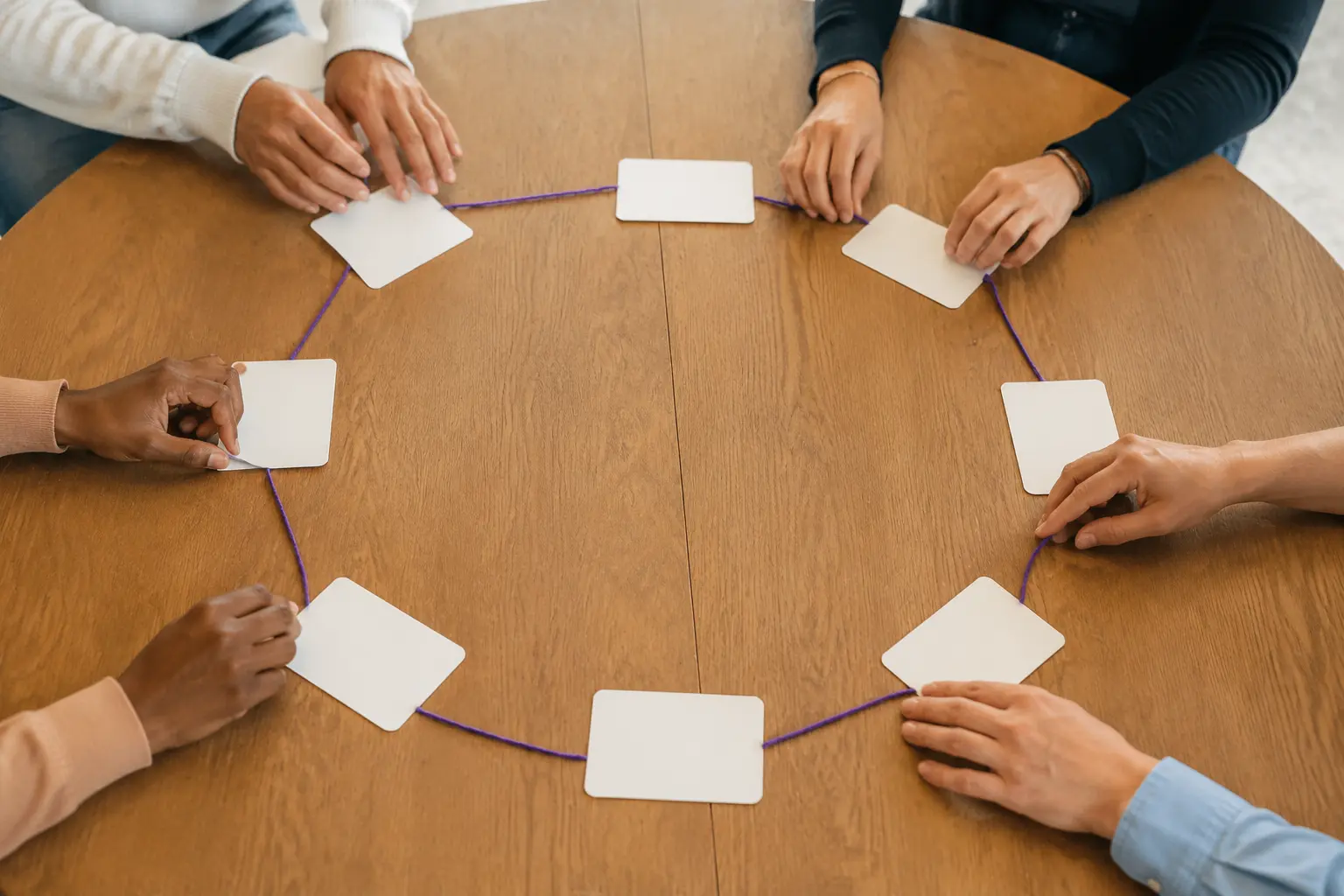Adult hands placing blank agenda cards across a shared table
